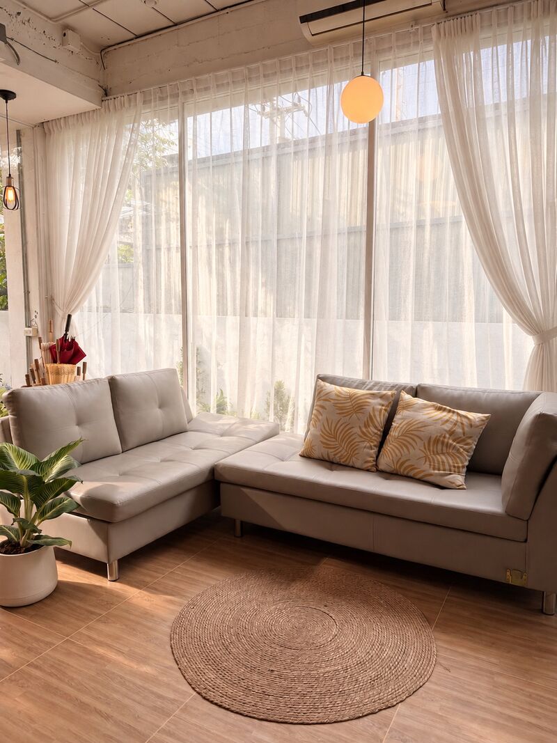 Lounge in our studio: a grey sofa, cushions and sheer curtains
