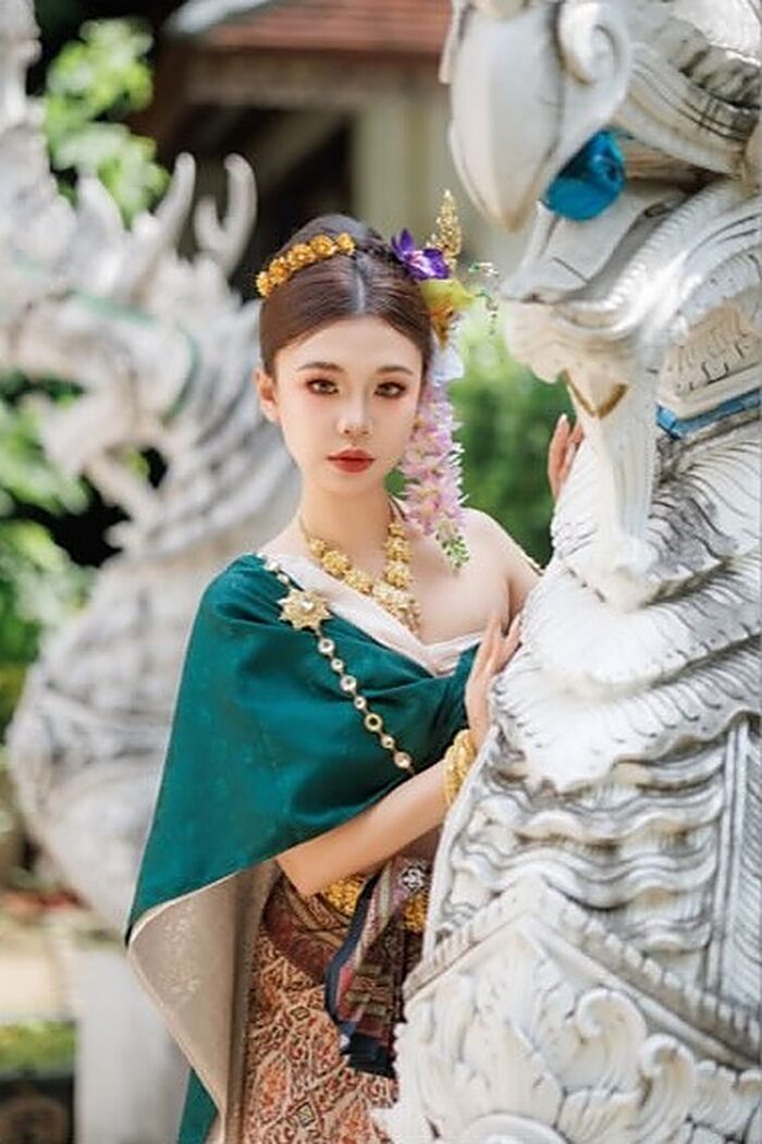 ชุดหยก: ผ้าคลุมไหล่สีเขียวมรกตกับเครื่องประดับทอง ข้างประติมากรรมแกะสลักสีขาว