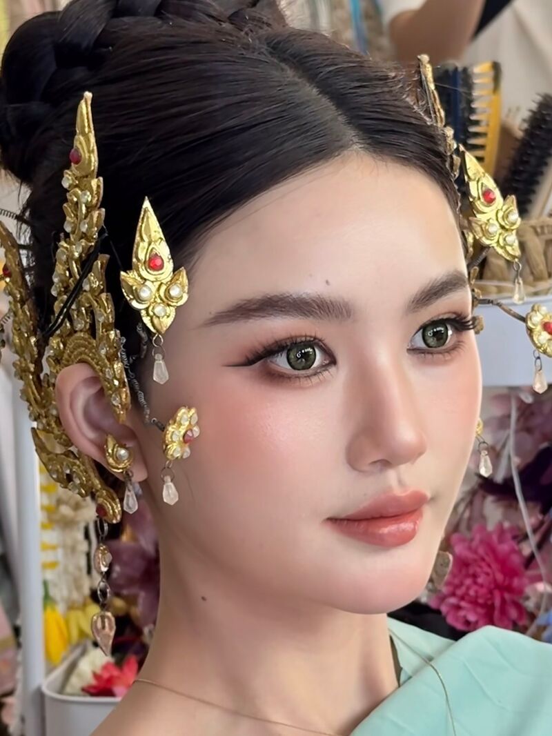 Close-up of soft make-up and a smooth updo, with gold ear ornaments and a mint silk shawl